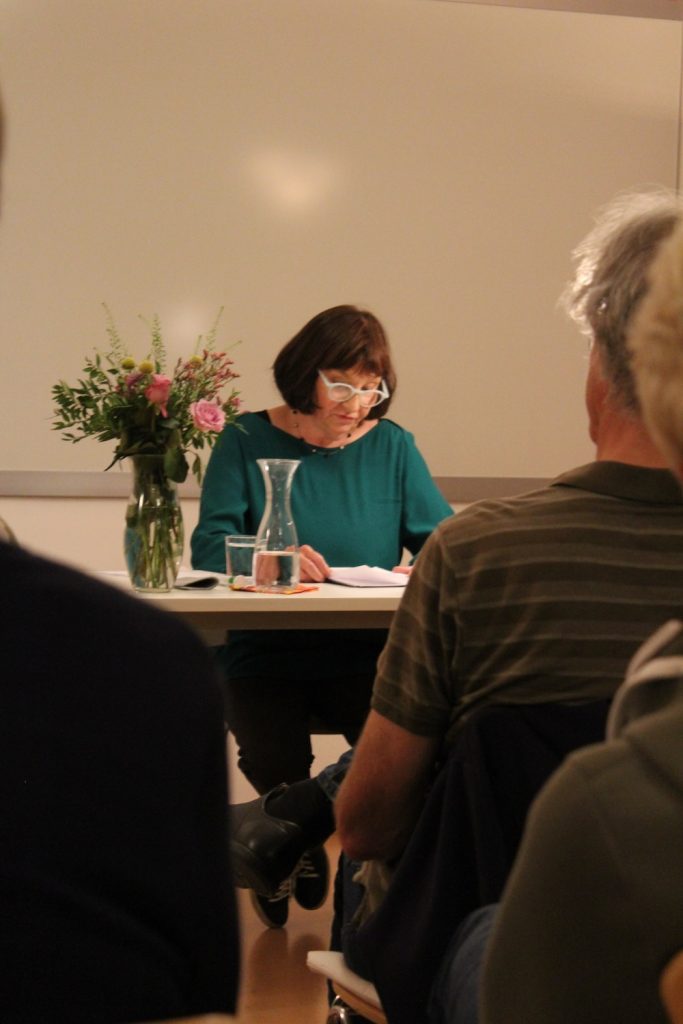 Impressionen der 1. Münchner Hospiz- und Palliativwoche im Oktober 2024. Eine Dame hält einen Vortrag vor Besuchern.